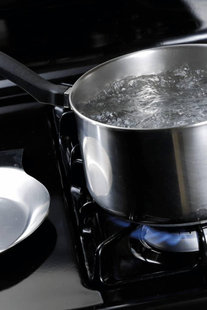 Move the water to a pot that was is not hot. This way the water will cool down much faster to room temperature
