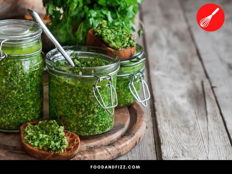 To retain the bright green color of basil in pesto, you can blanch the basil leaves, add lemon juice, protect it a ziploc bag before rolling, or mist oil on leaves before cutting.