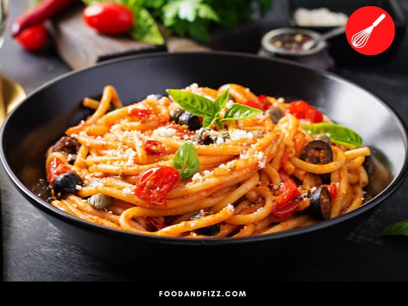 Spaghetti Alla Puttanesca is made with tomatoes, olives, anchovies, capers, garlic, chili and olive oil.